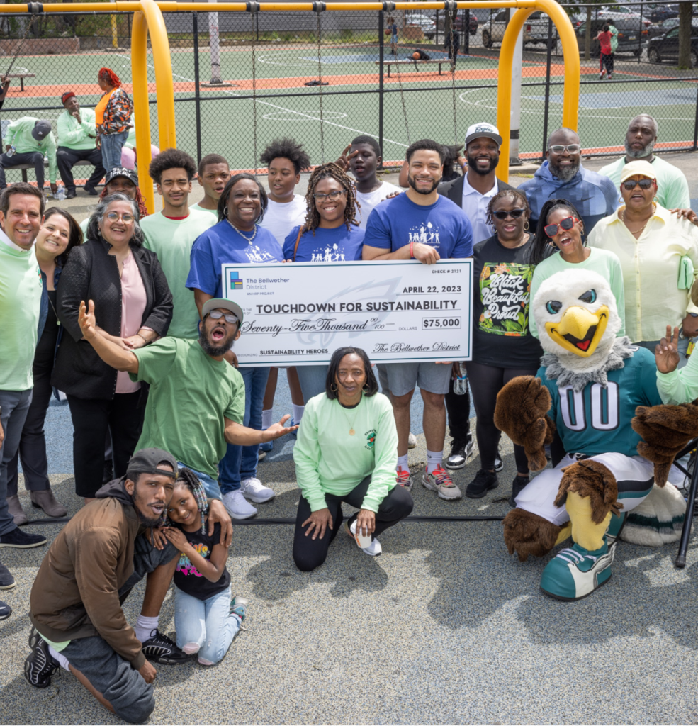 A group poses with a giant check made out to Touchdown for Sustainability